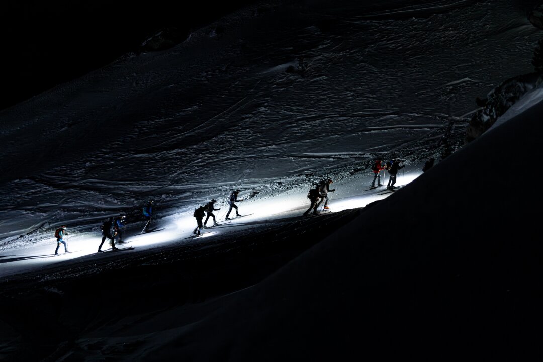 Skieurs-alpinistes en progression de nuit lors de la Patrouille des Glaciers en Suisse